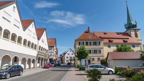 Mann zeigt auf eine digitale Karte mit blauen, roten und grauen Punkten auf einem großen Bildschirm in einem Büro.